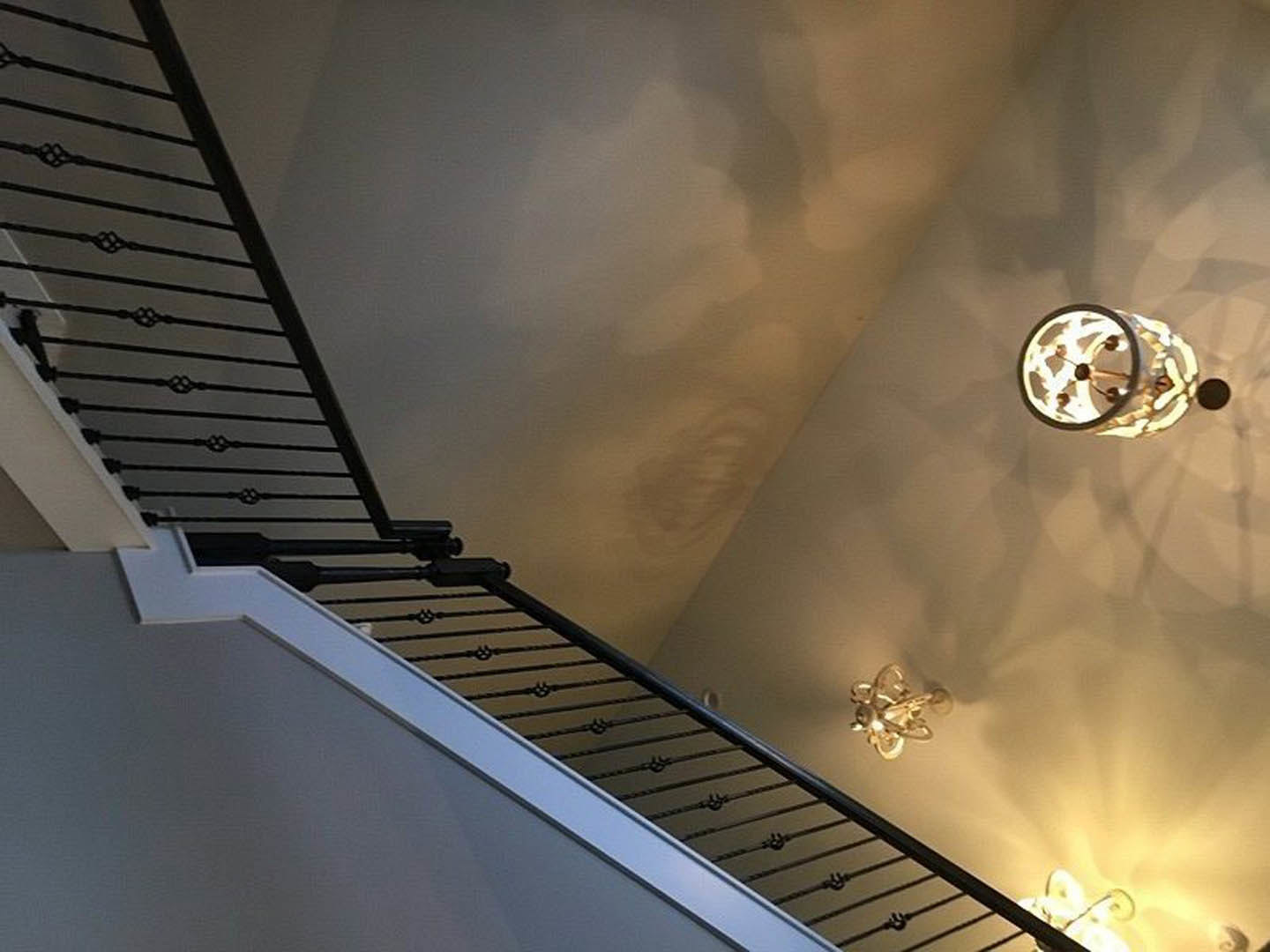 Modern pendant light with frosted glass shade hanging above wooden staircase with metal railing and white walls
