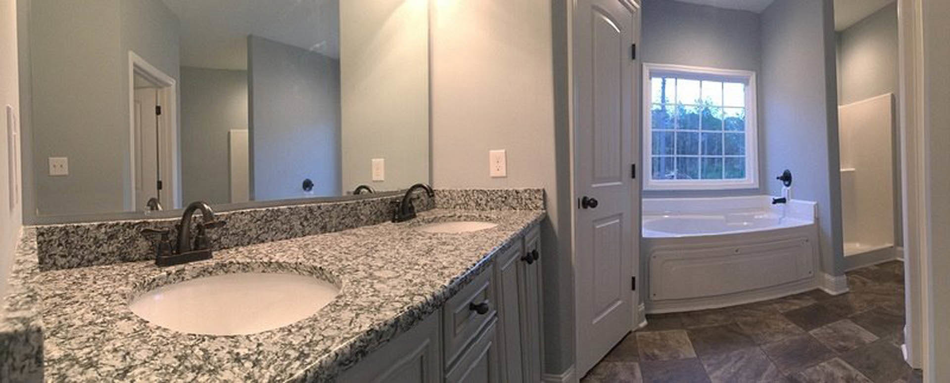 Bathroom featuring marble countertops, chrome faucet, white cabinetry, and neutral wall tiles