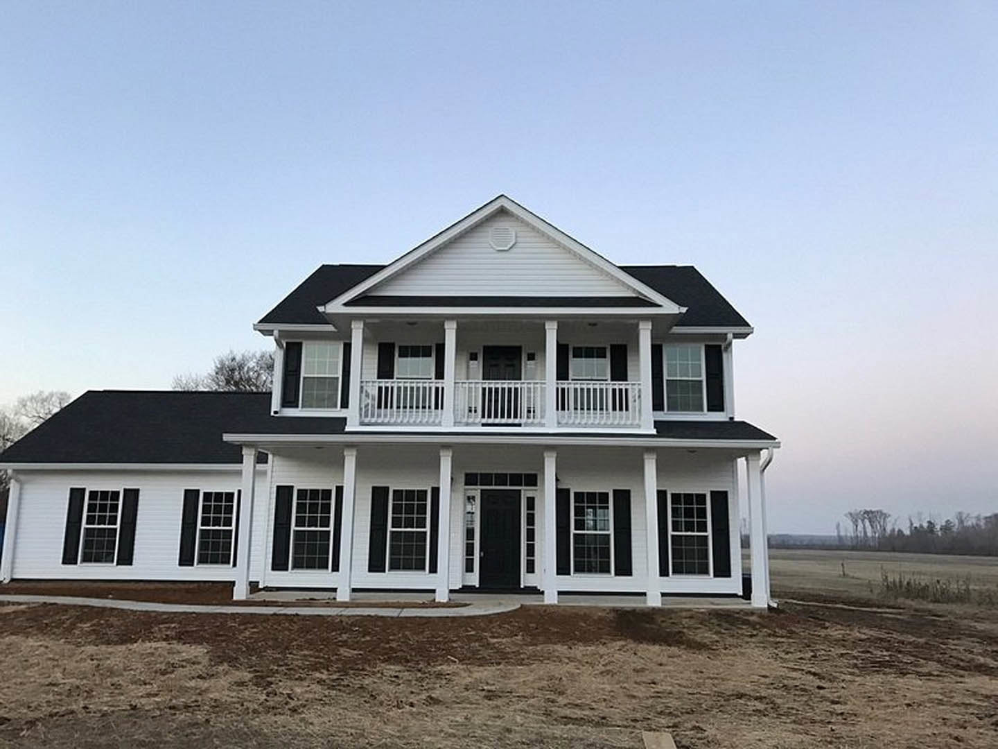 White siding house with black roof, black shutters, white porch railing, square windows with white frames, and black front door with white trim