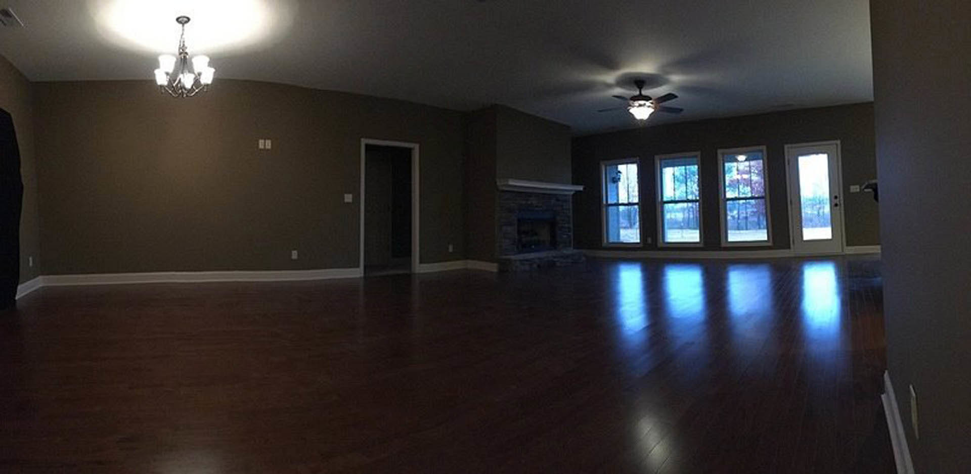 Living room with plaster walls, laminate flooring, stone fireplace, and ceiling fan with light fixture