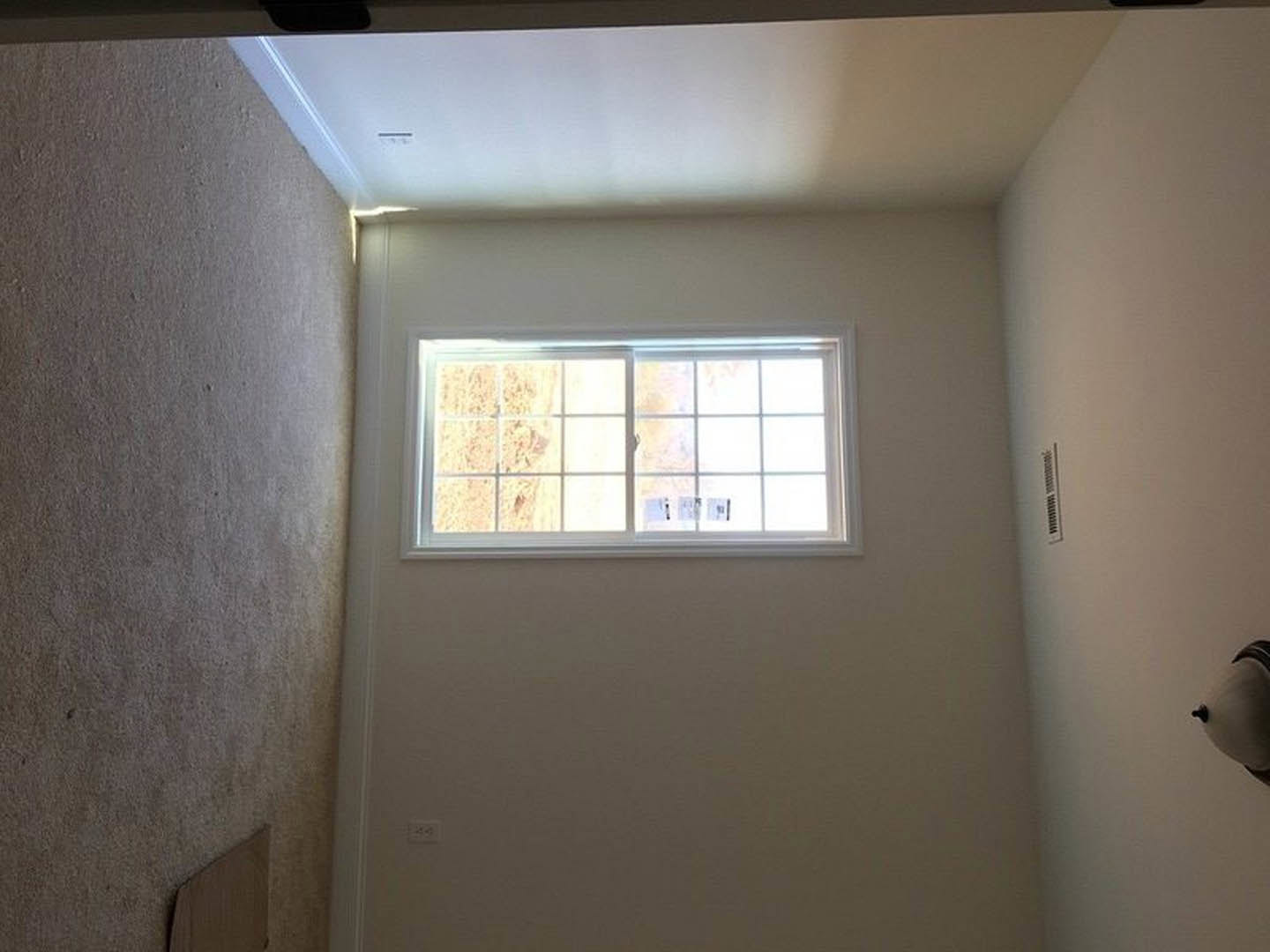 Bright room with white plaster walls, multi-pane window with white trim, ceiling fixture, and window blinds