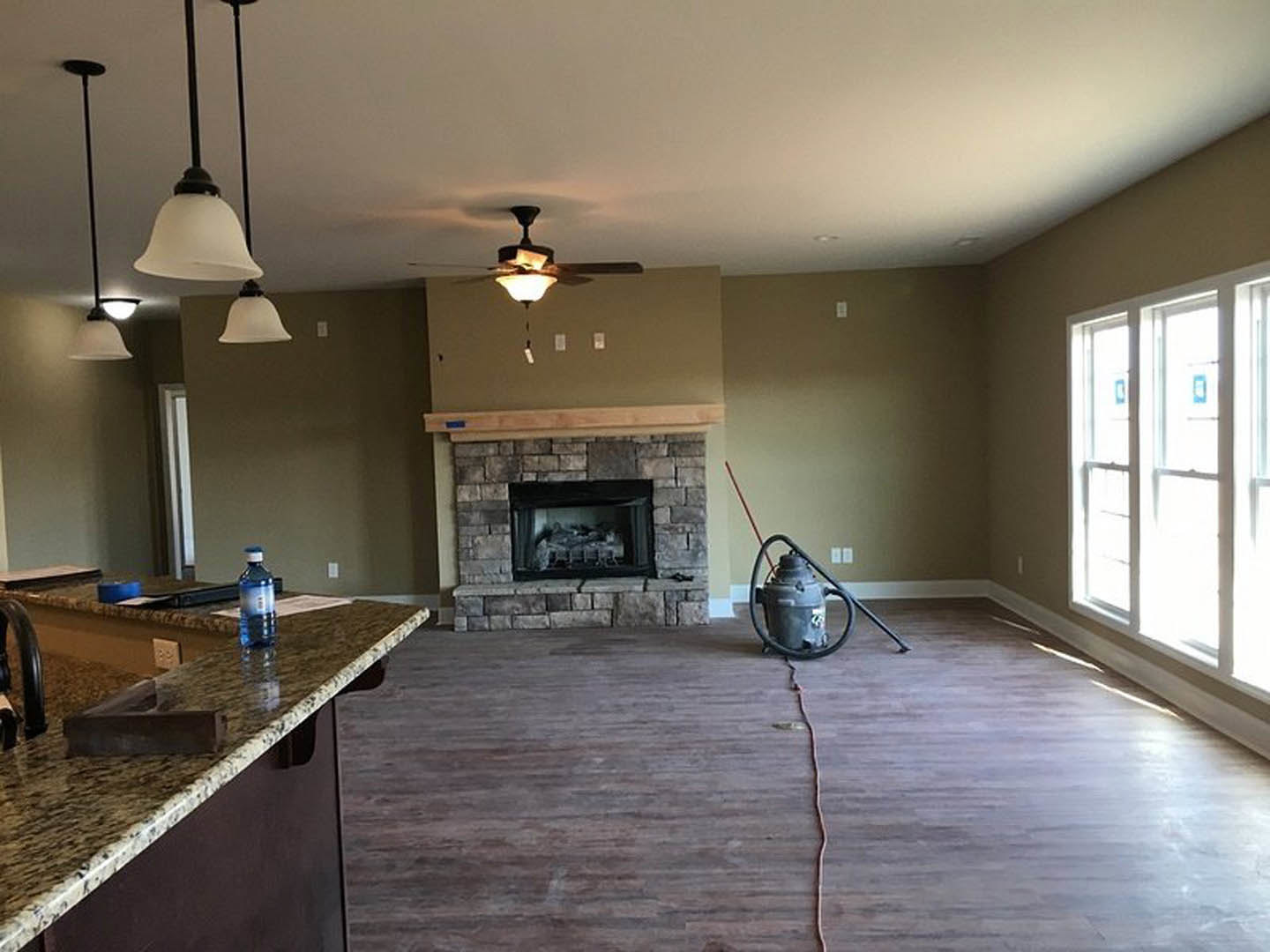 Living room featuring a black-framed glass fireplace, wooden flooring, vacuum cleaner near the fireplace, white door with window panes, water bottle on a countertop