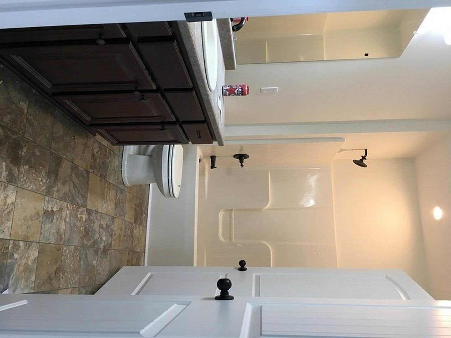 Modern bathroom featuring white tile walls, a sleek vanity with undermount sink, chrome faucet, white toilet, glass shower door, and light wood cabinetry