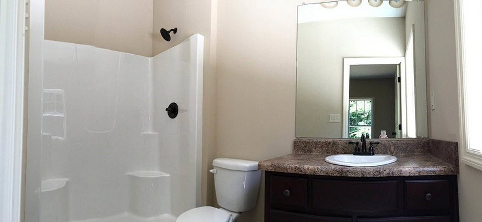 Modern bathroom featuring a glass-enclosed shower, white porcelain sink and toilet, light gray tile walls, chrome fixtures, and recessed lighting