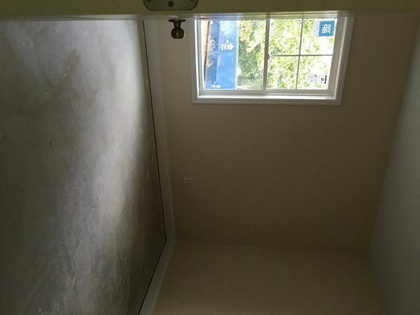 White plaster walls, black door with metal handle, window with white frame allowing daylight into minimalist room