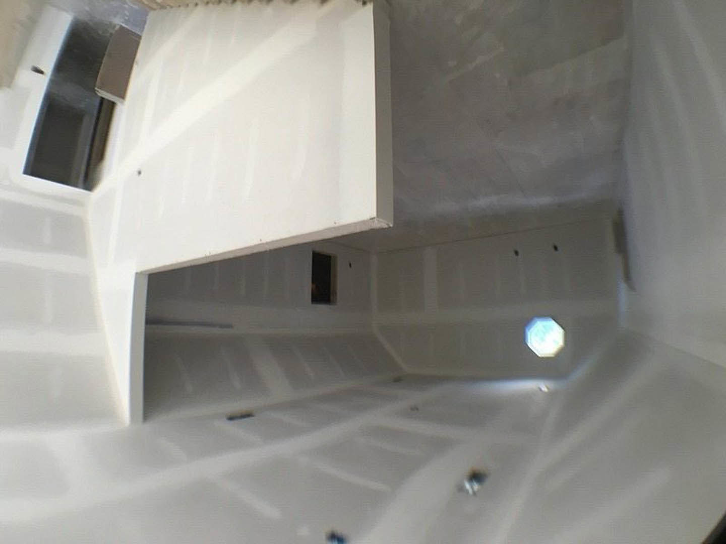 Bright room with white walls, large window, metal-framed door, and minimal furnishings