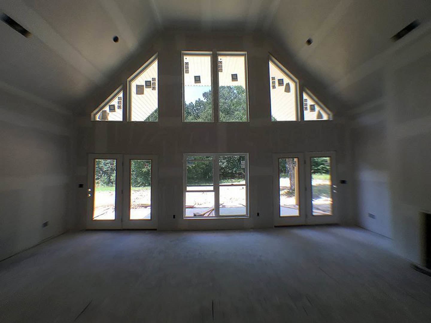 Sunlit room featuring multiple large windows, light wood flooring, white walls, and a smooth white ceiling.