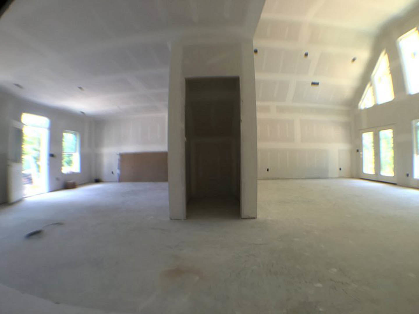 Bright room with white plaster walls, large windows, white door, and light-colored flooring