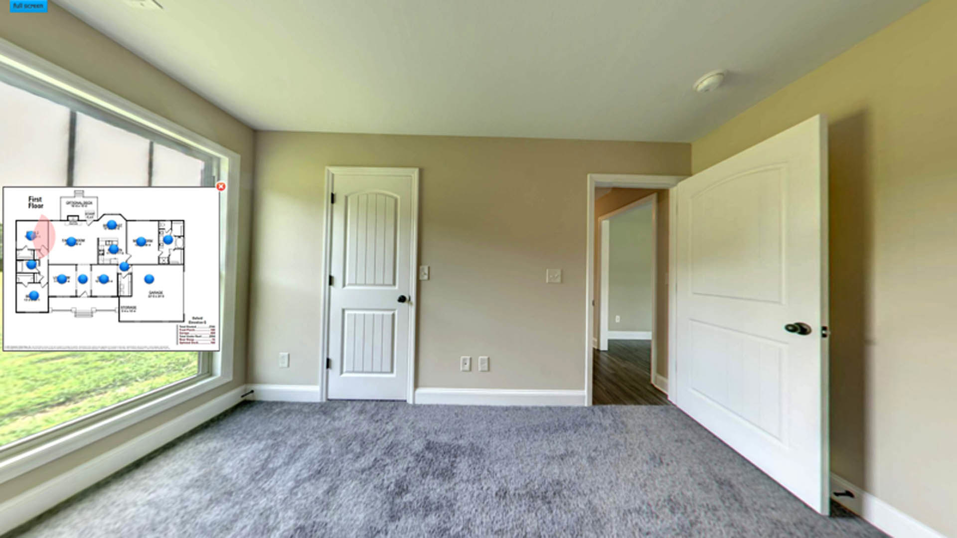 White paneled door with black handle opening into a carpeted room with light-colored walls and baseboards