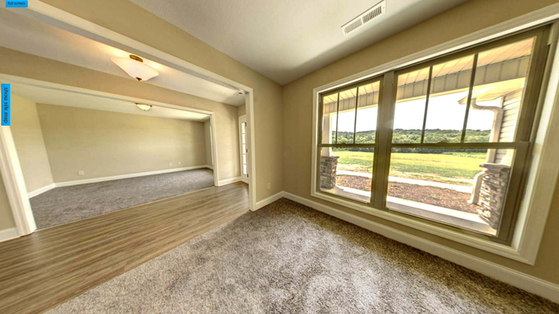 Spacious room featuring wide wood plank flooring, large window overlooking grassy field, neutral walls, and ceiling with recessed lighting