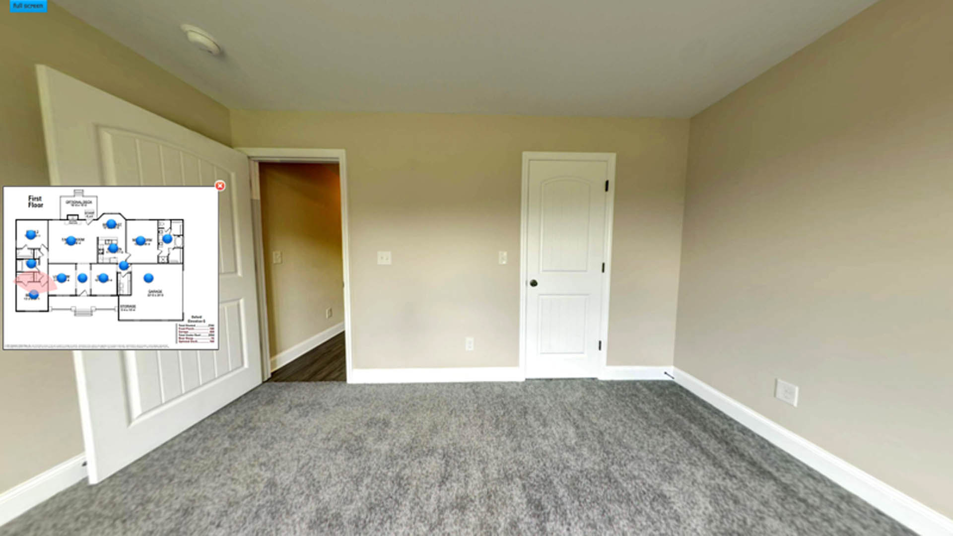 White door with black handle set in a room featuring grey carpet flooring, white walls, and a light switch.
