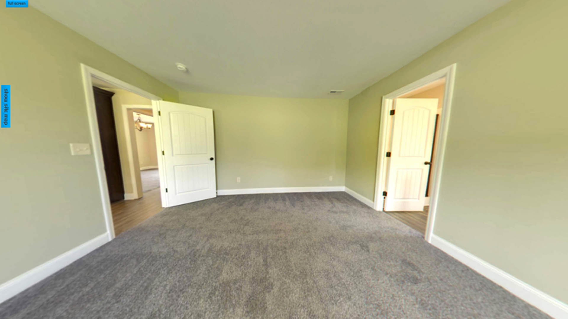 Carpeted room with two white doors featuring black handles, white walls, and ceiling