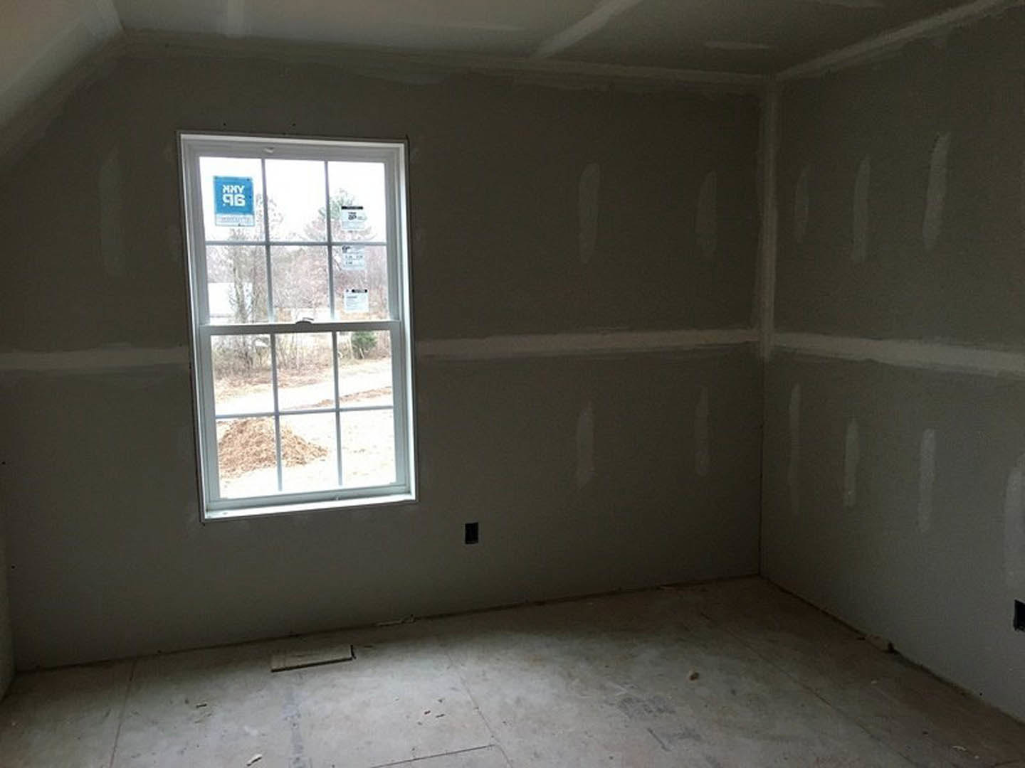 Concrete floor and plaster walls in a bright room with a large window, ceiling light fixture, and daylight streaming in.