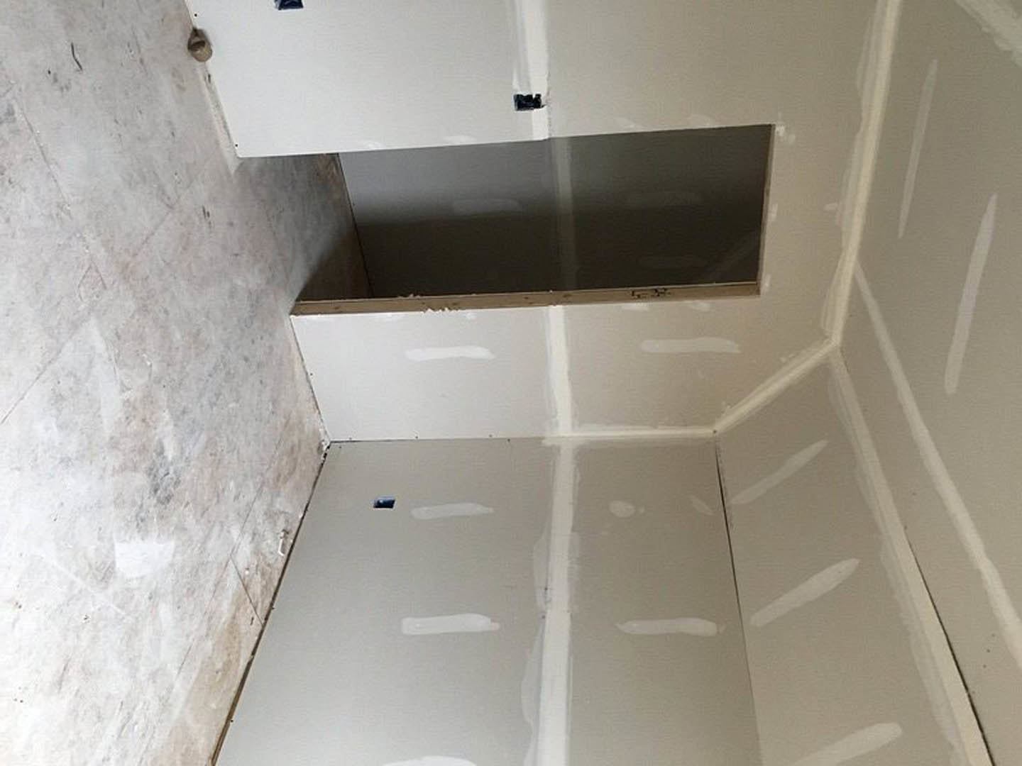 White bathroom with marble tile floor, plaster walls, black accent wall, blue and black flag decor, and a door adjacent to a wall opening.