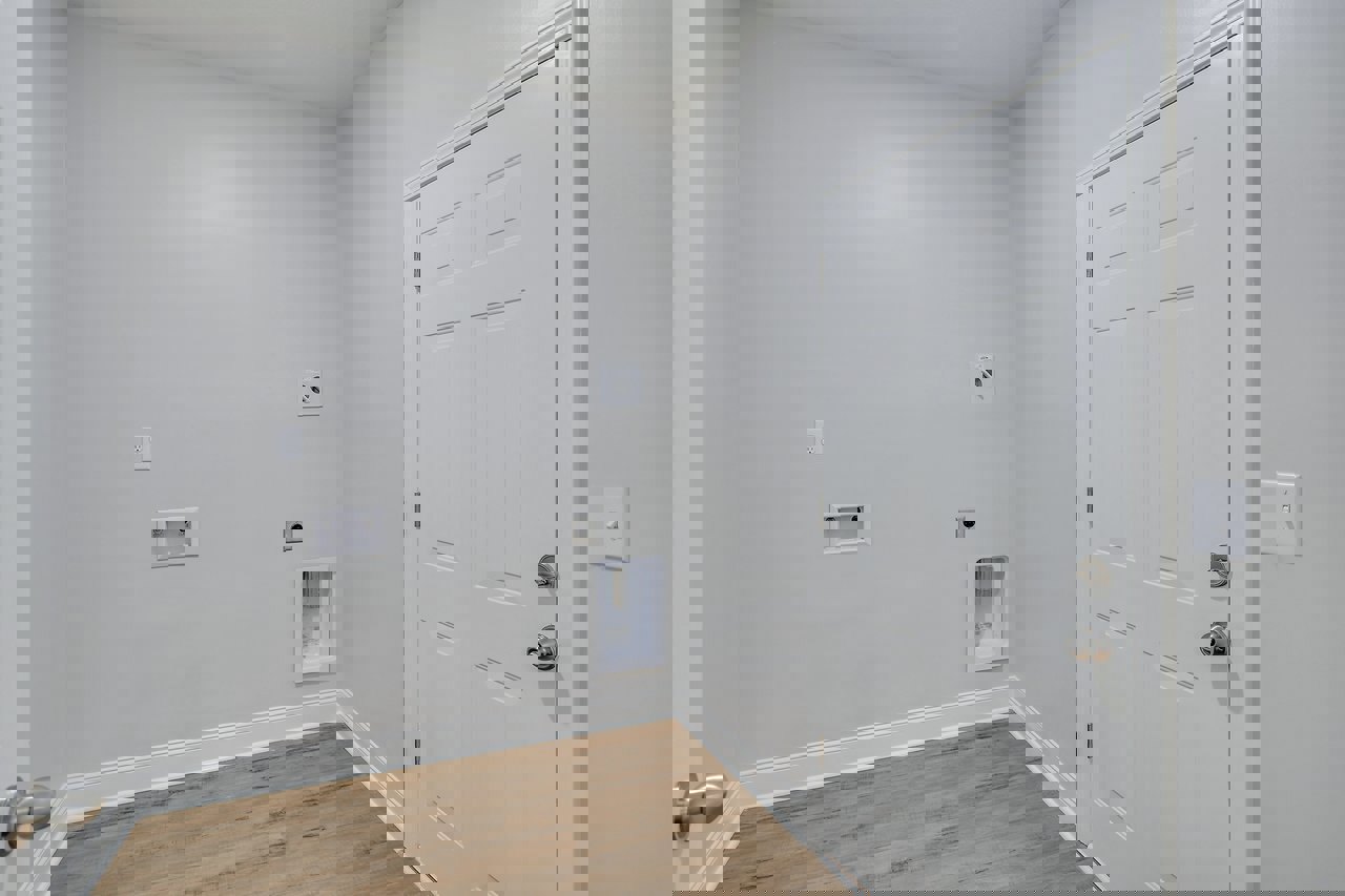 White paneled door with silver handle and clear glass window, set in a room with wood flooring and white baseboard trim.