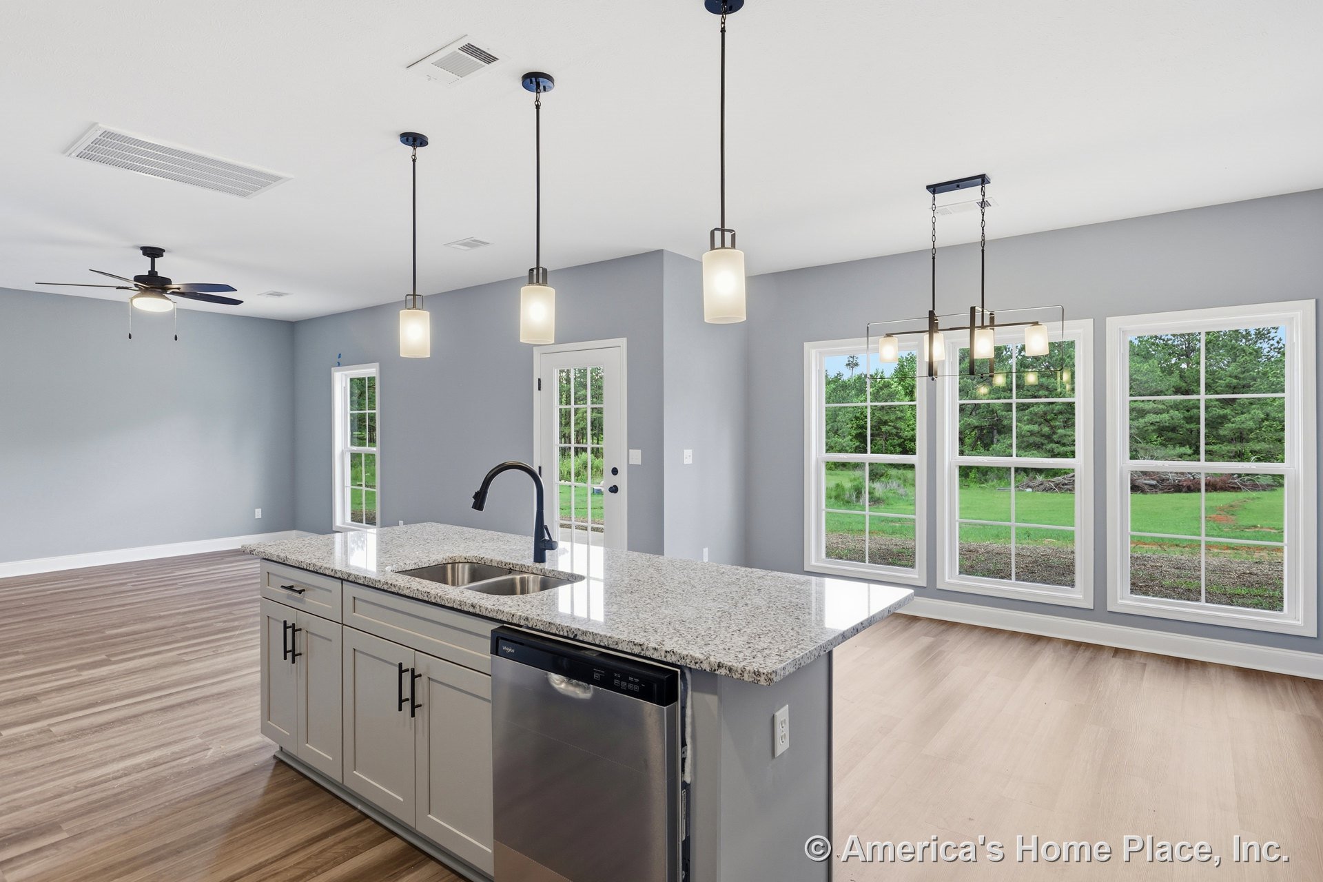 Granite countertop island with white shaker cabinetry, stainless steel dishwasher, three pendant lights, large picture windows, light wood flooring, gray walls, and open floor plan