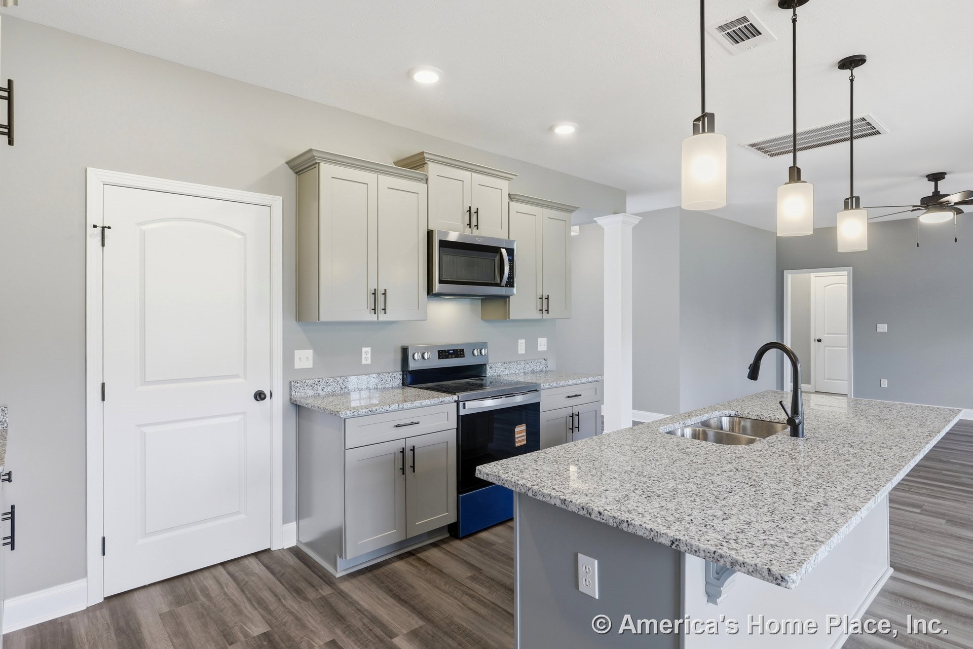 Gray shaker cabinets with granite countertops, stainless steel appliances, pendant lights above a central island, double bowl undermount sink, wood-look vinyl plank flooring, white