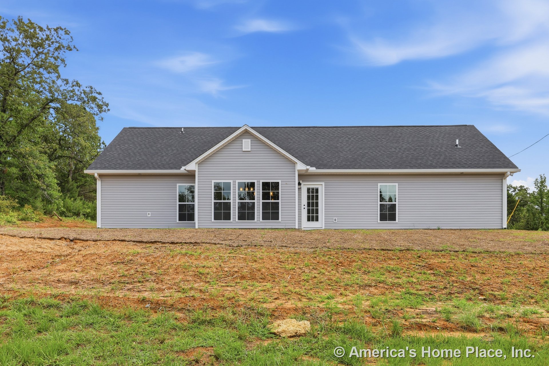 Gray vinyl siding single-story home with gable roof clad in asphalt shingles, large grid windows with white trim, glass panel exterior door, and gable vent.