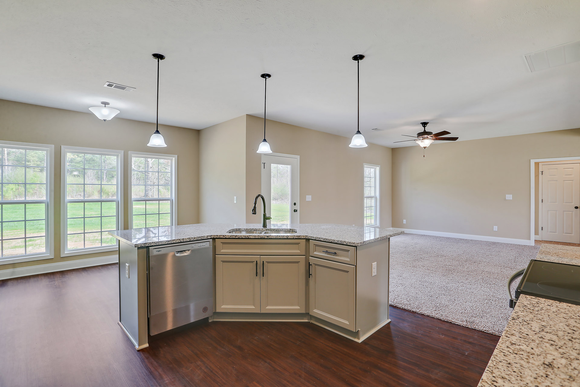 Modern kitchen featuring tile flooring, white cabinetry, stone countertops, stainless steel sink, expansive ceiling, black structural pole, white door with black handle, and window