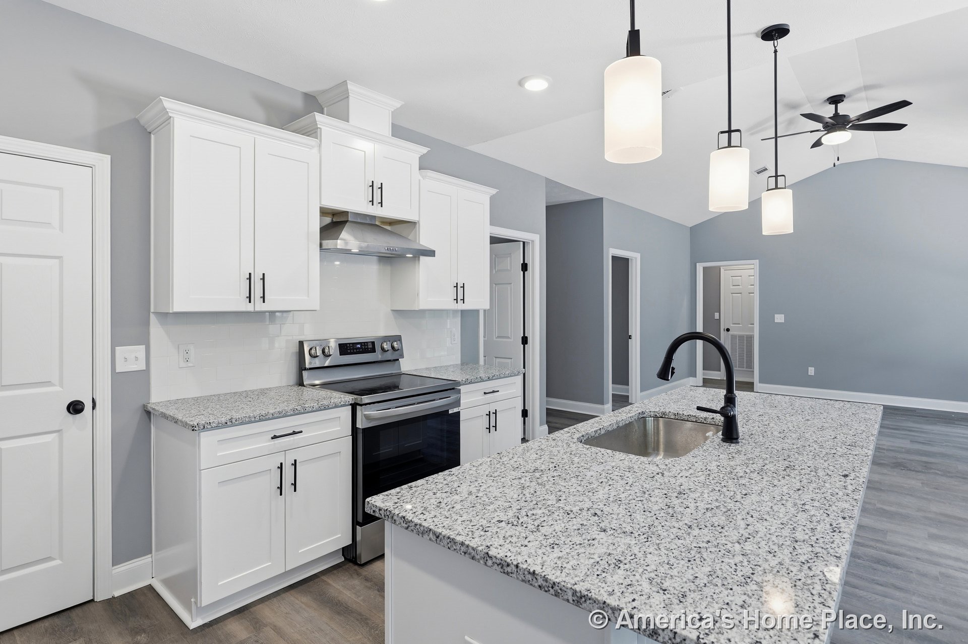White shaker cabinets, granite countertops, stainless steel range and hood, tile backsplash, large island with pendant lighting, single bowl sink with matte black faucet, gray