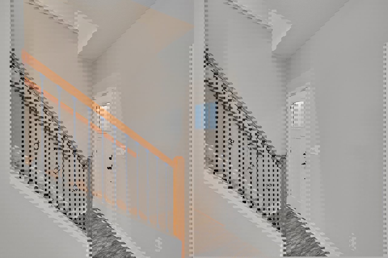 Wood staircase with black metal railings, white walls, white door with black knobs, wood flooring, window close-up, wall-mounted light fixture