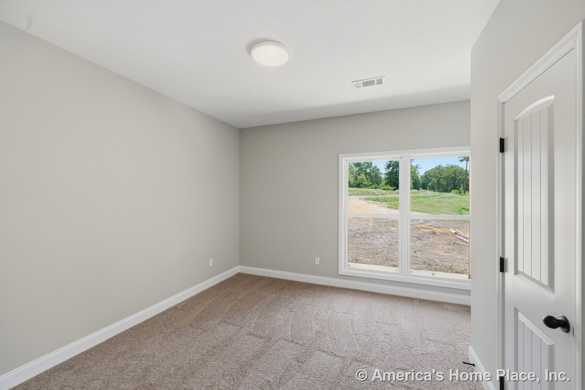 Bedroom with large double window framed in white trim, neutral painted walls, carpet flooring, white baseboards, paneled interior door, and flush ceiling light fixture.