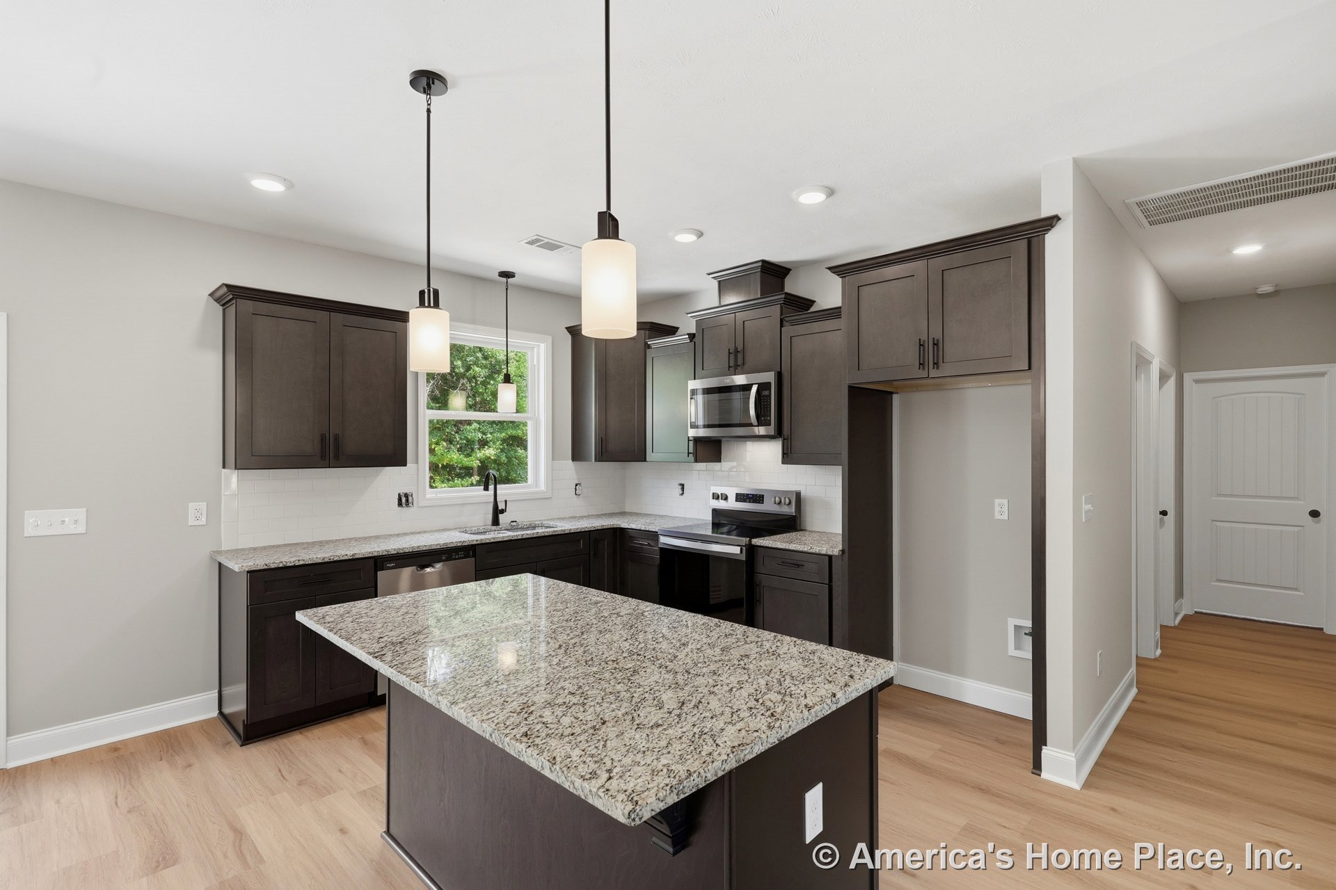 Dark wood cabinetry and upper cabinets, granite island countertop with pendant lighting, stainless steel appliances, white subway tile backsplash, recessed ceiling lights, light
