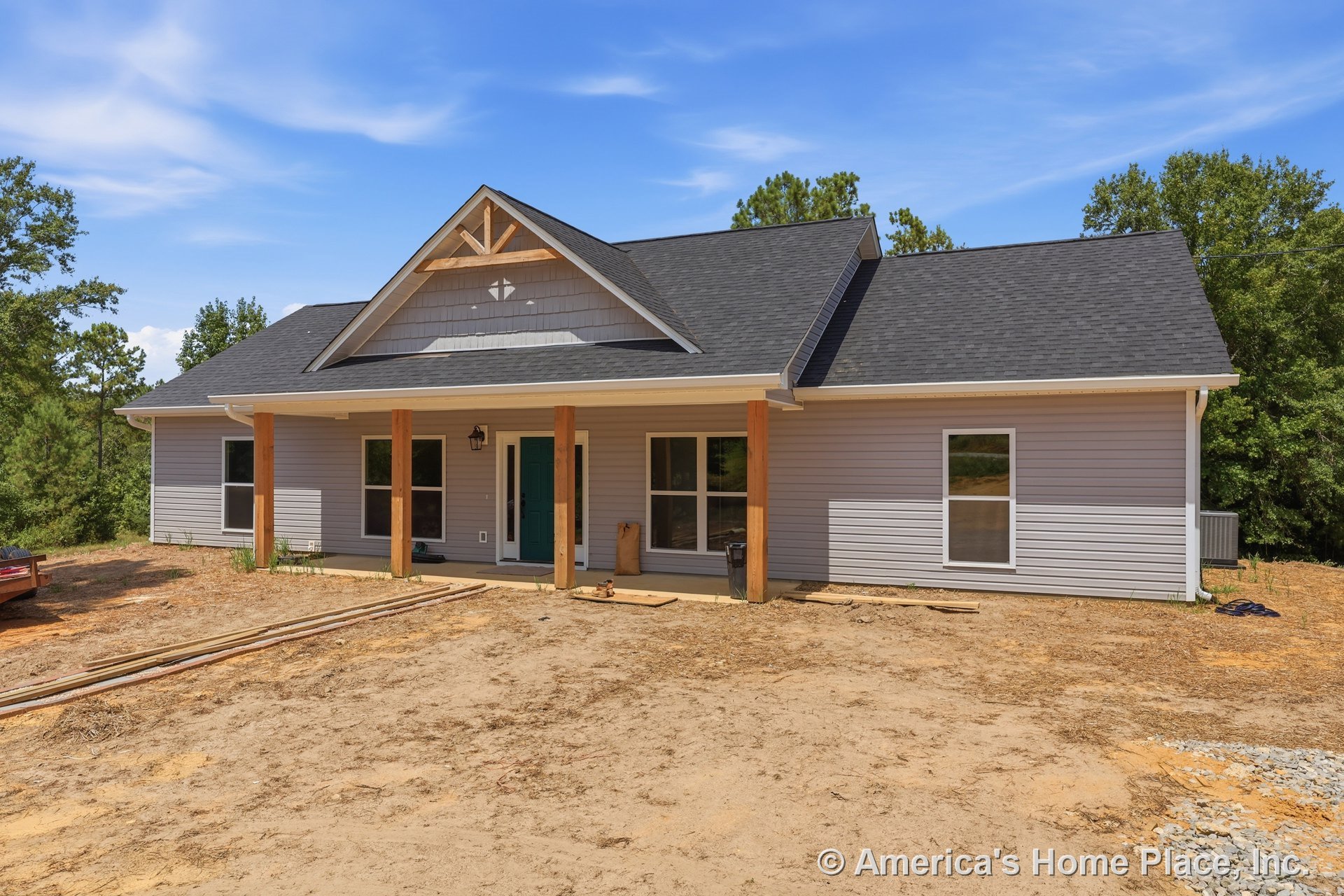 Covered front porch with wooden support columns, gabled roof, gray vinyl siding, multiple windows, teal front door, white trim, and outdoor lighting fixtures.