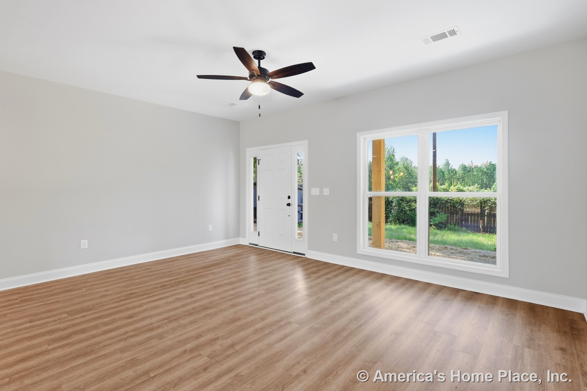 Light wood-look vinyl plank flooring, white trim and baseboards, large double window with white window trim, ceiling fan with integrated light fixture, neutral wall color, front