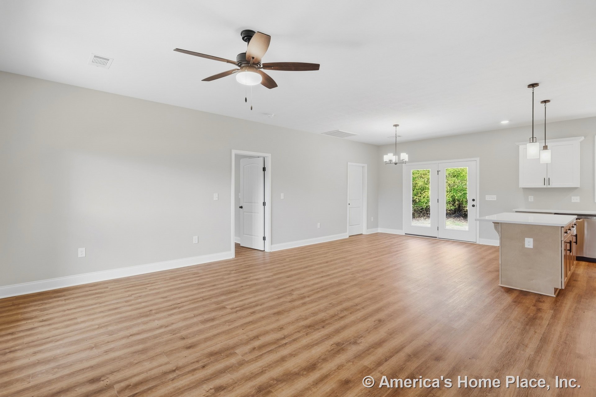 Open concept living area with wood-look plank flooring, ceiling fan with light, kitchen featuring white cabinetry, quartz countertops, pendant lights above island, recessed