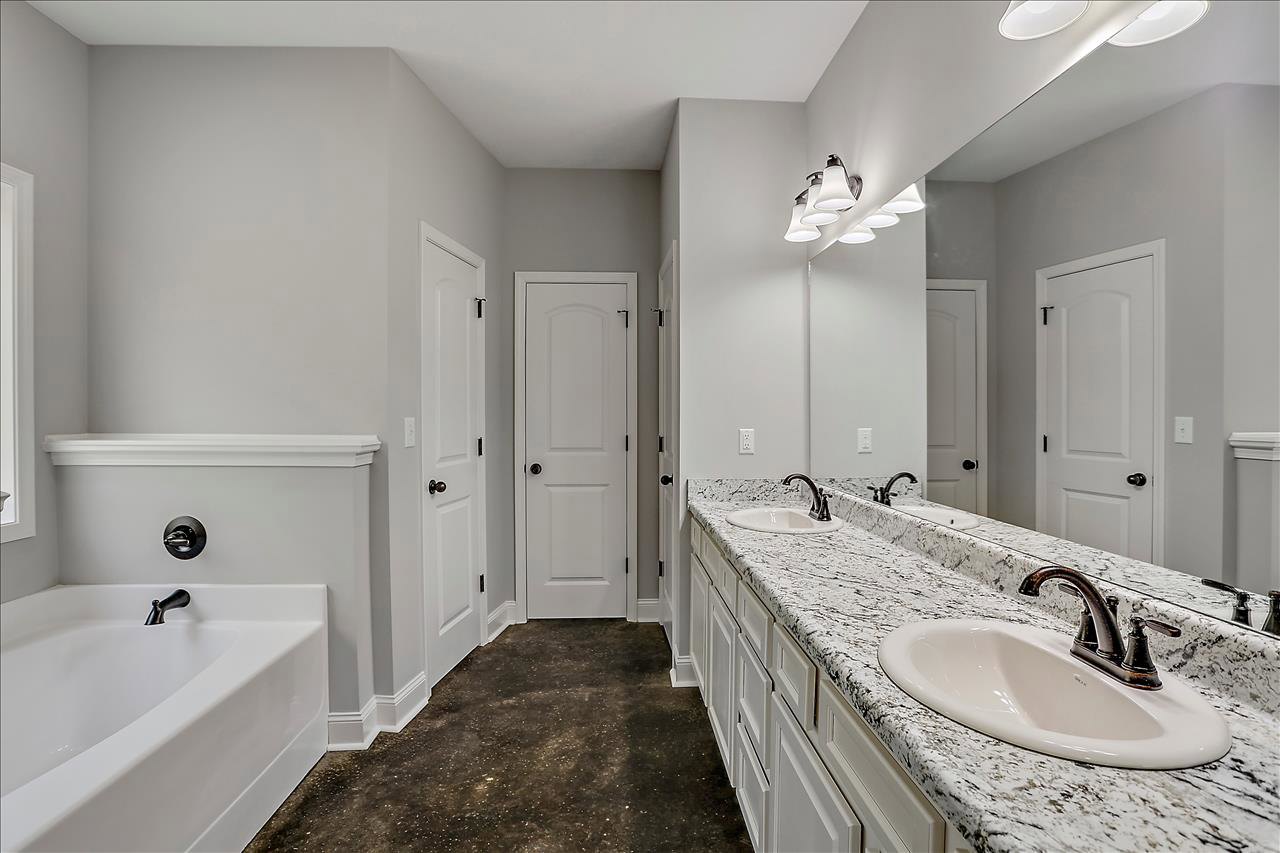 Bathroom featuring marble countertops, white bathtub with black faucet, white door with black knobs, and sink with marble surface