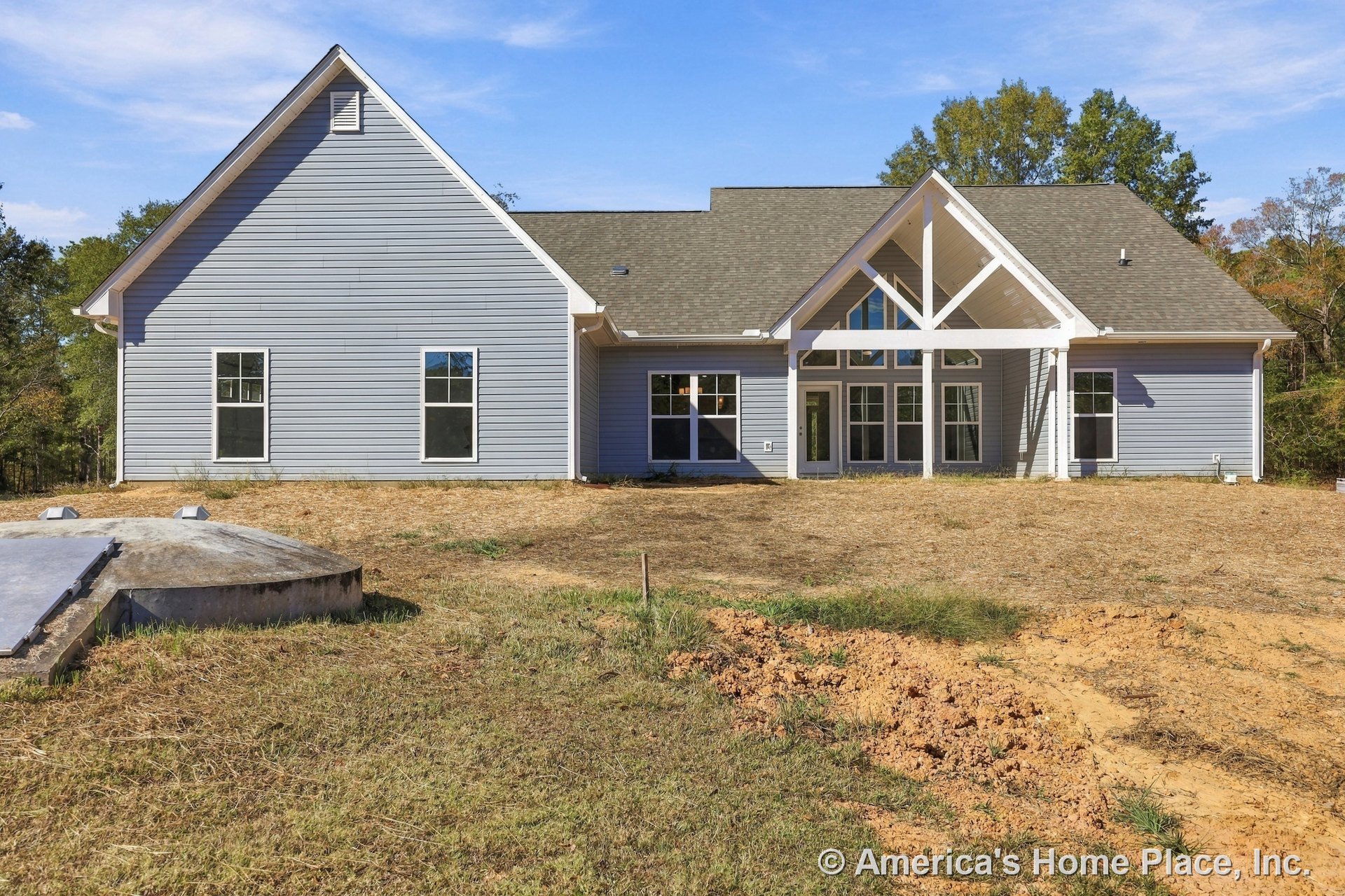Gray vinyl siding exterior with multiple rectangular windows, gable roof, white trim accents, and a covered rear porch featuring exposed beams and porch columns.