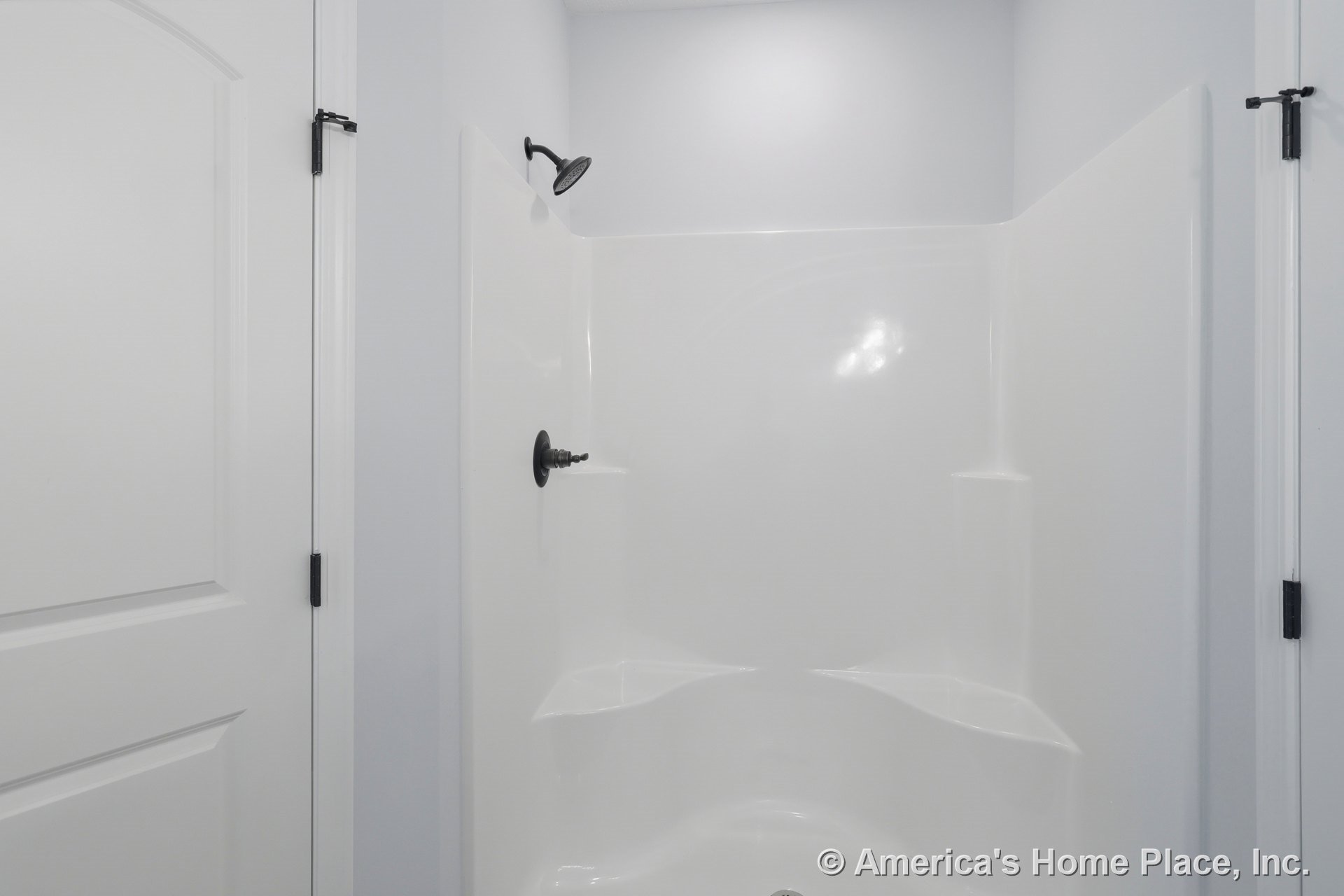 Matte black shower head and handle mounted on white tiled bathroom wall
