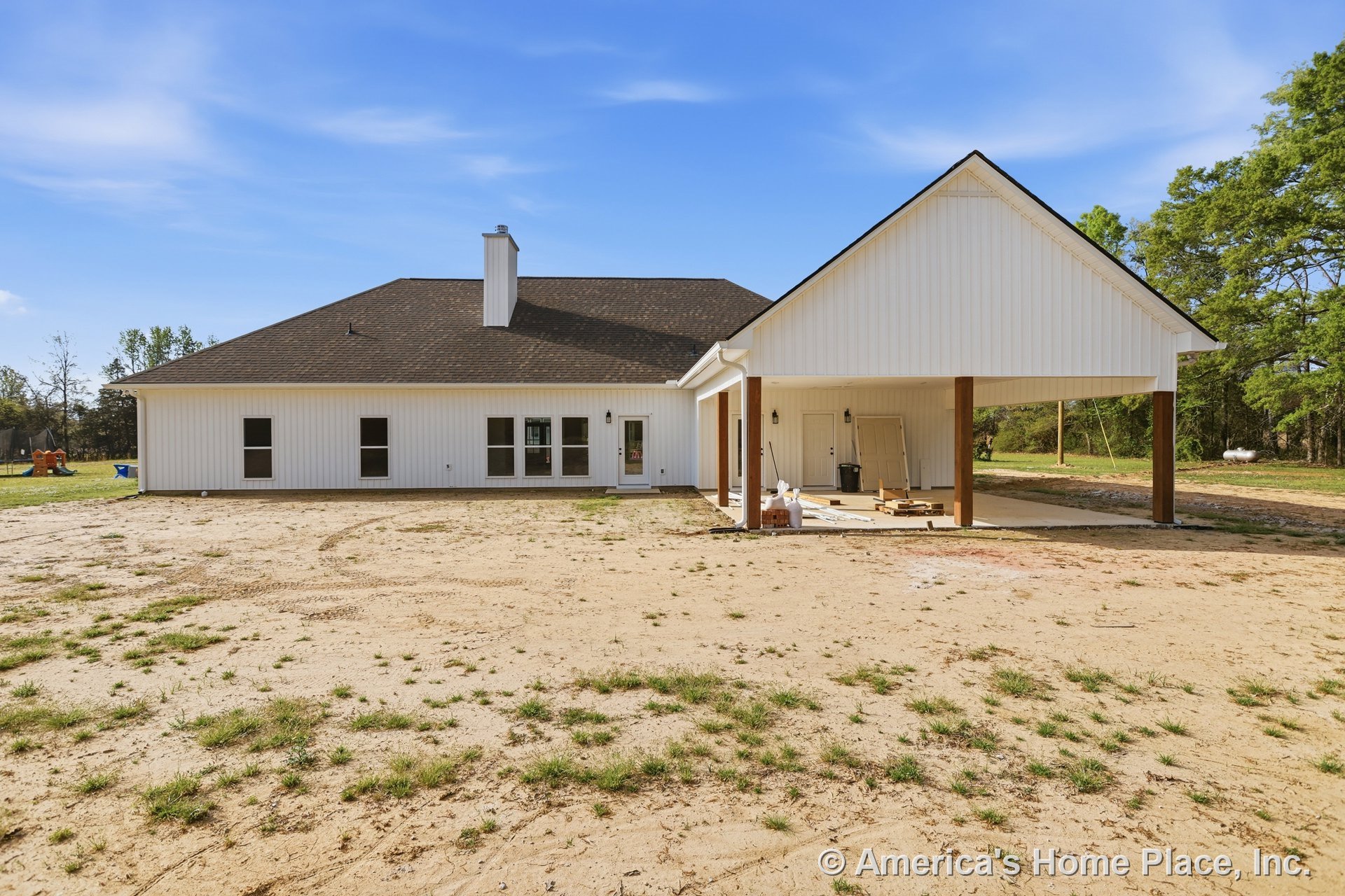 White-roofed house with brick chimney, surrounded by a spacious grassy yard and mature trees under a partly cloudy sky