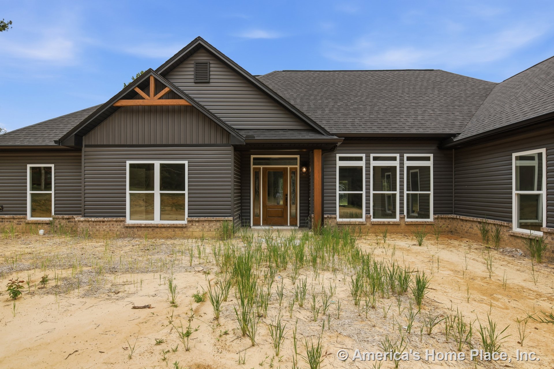 Dark horizontal siding and brick foundation trim accent a custom home exterior with a covered front entry, wooden support column, double front door featuring glass panels, gable