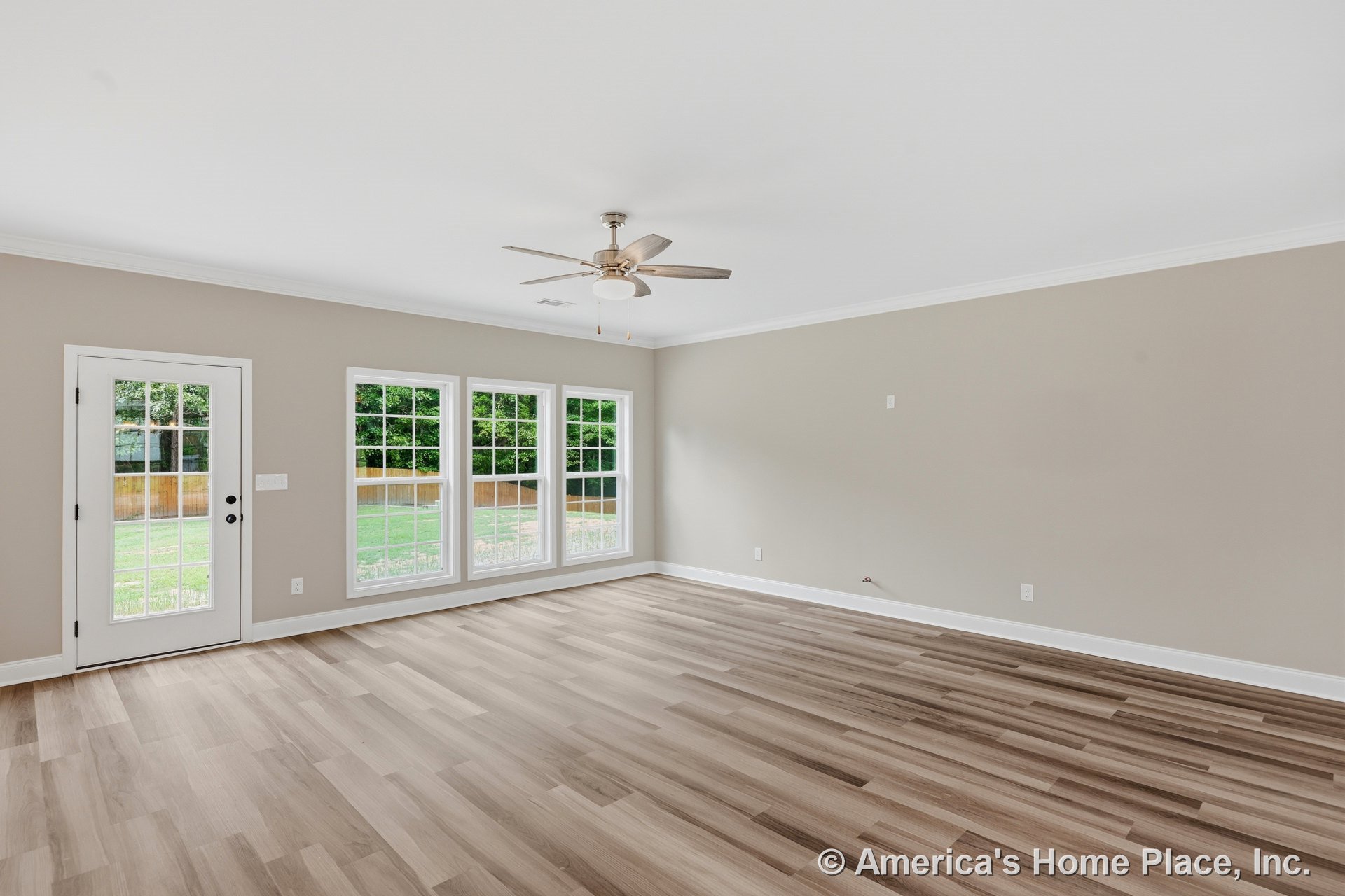 Living room with large grid windows, glass exterior door, wood-look plank flooring, neutral wall paint, white crown molding and baseboards, ceiling fan with light, and abundant