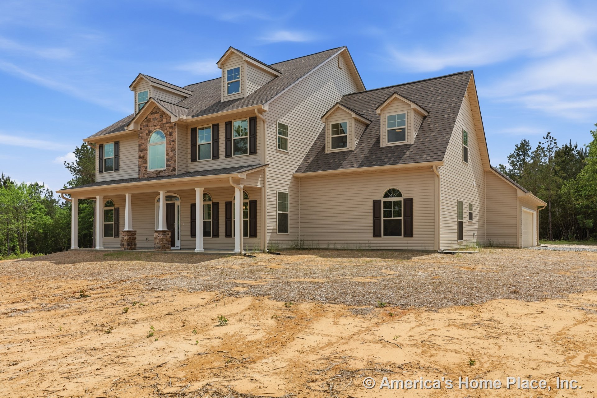 Two-story exterior with beige siding, stone accents, and gabled roof; covered front porch supported by columns; arched windows with black shutters; stone trim framing entry