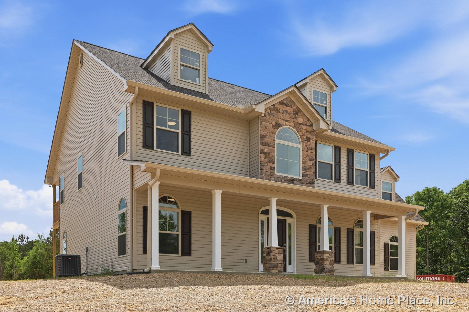 Beige siding exterior with stone veneer facade, arched windows, white porch columns, black shutters, gabled dormers, double front doors, and detailed trim.