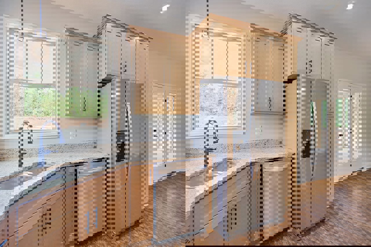 Kitchen with stainless steel refrigerator, wooden cabinets, silver dishwasher, chrome faucet, glass door, and pendant light fixture