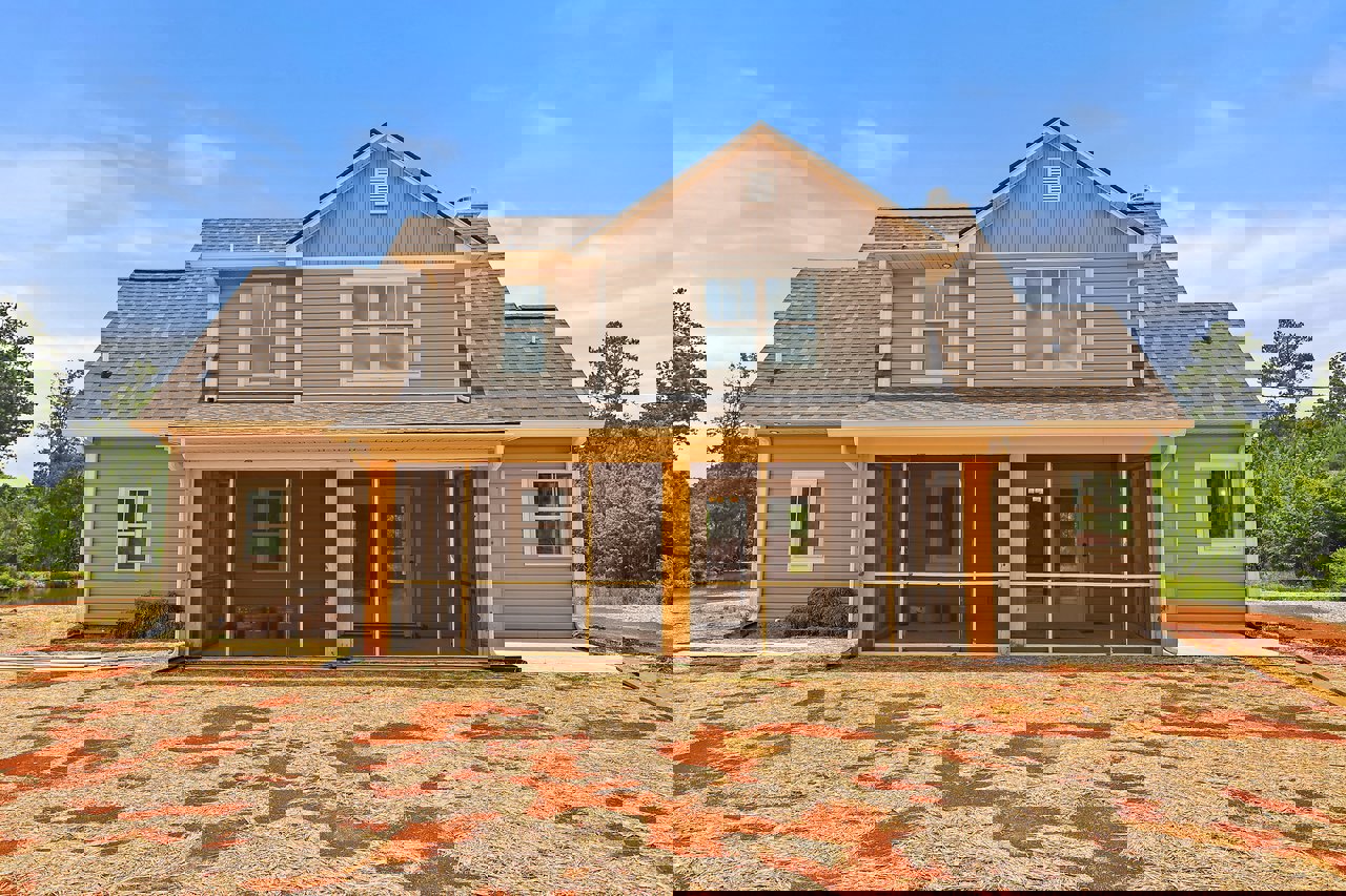 Two-story home with gray siding, screened front porch, white-framed windows, shingled roof, and straw-covered yard.