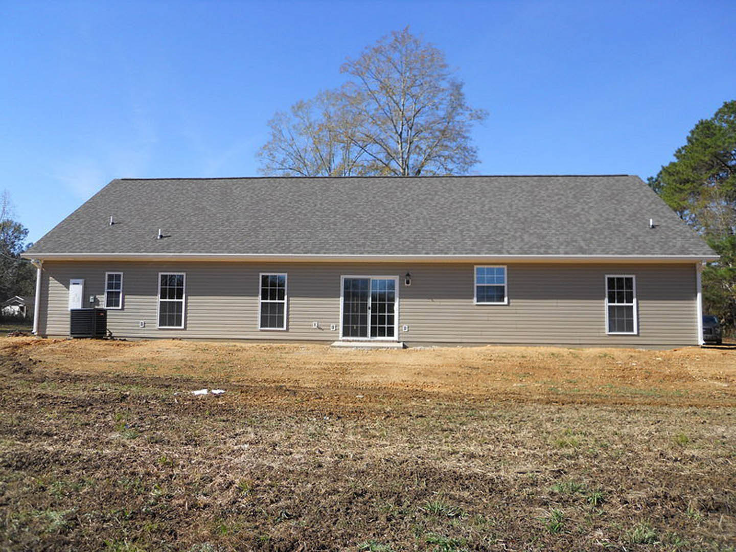 Two-story home with white siding, covered front porch, large grassy yard, leafless tree, and white-framed windows