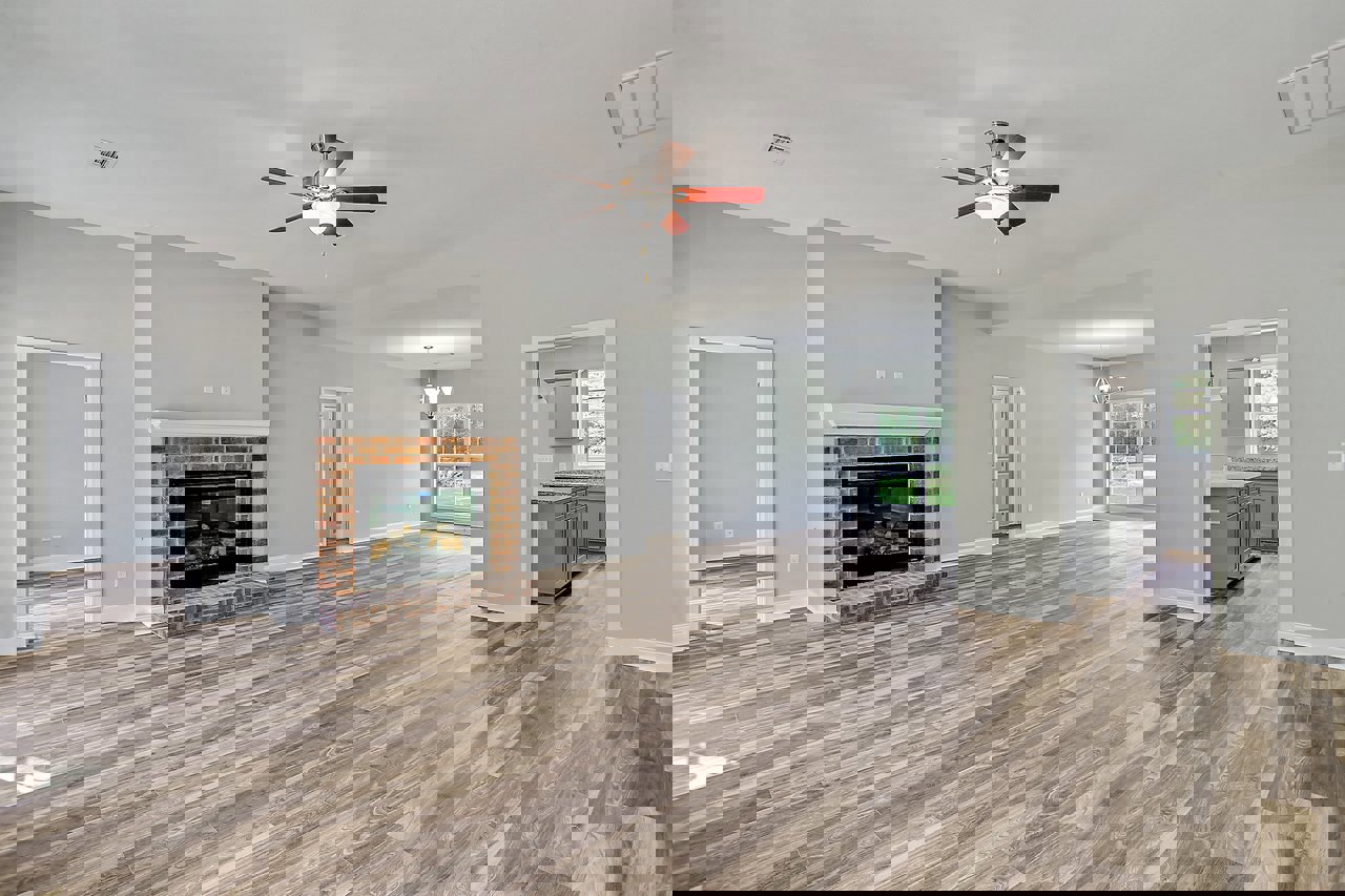 Living room with hardwood floor, ceiling fan with light fixture, black glass fireplace, white walls, and white door frame