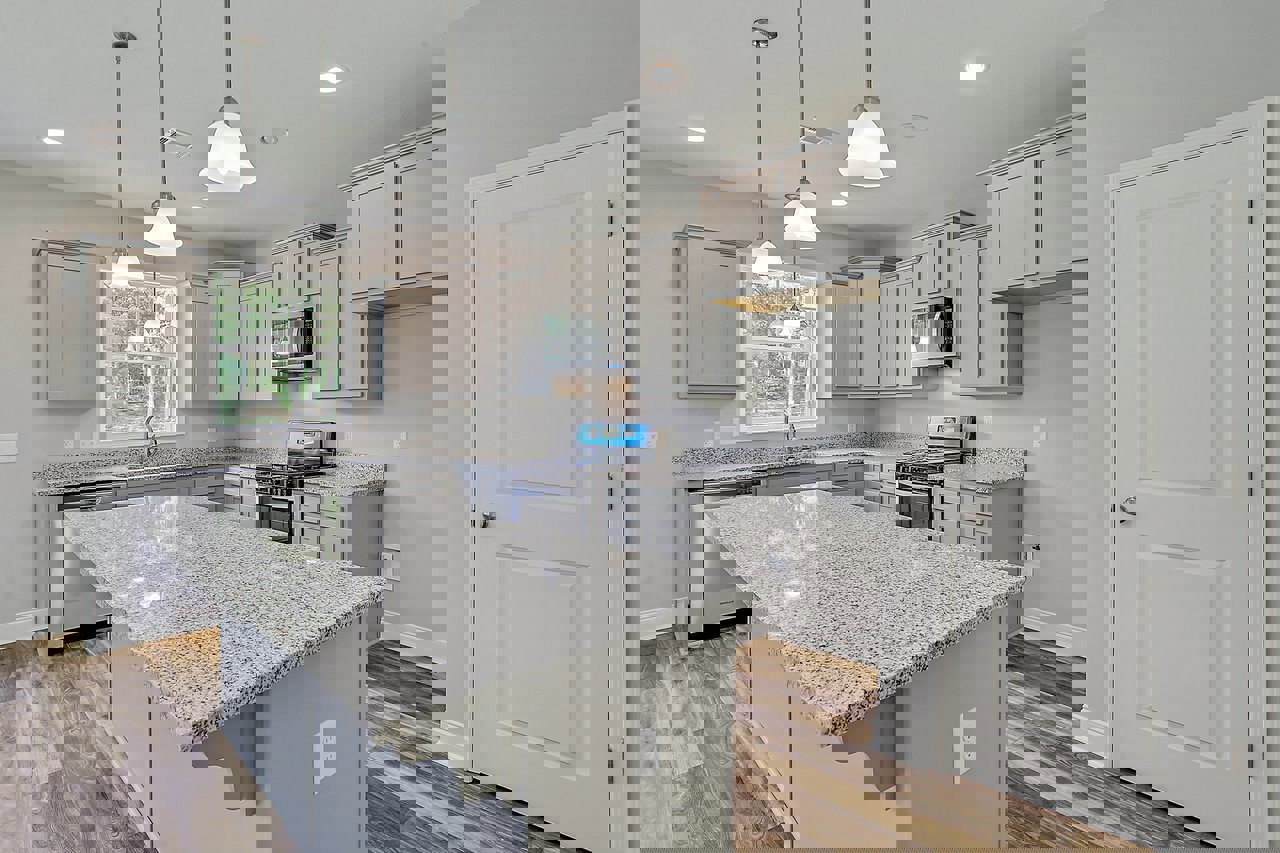 Marble countertop kitchen with tile backsplash, stainless steel appliances including microwave and stove, white cabinetry, silver hardware, and white door with silver knob