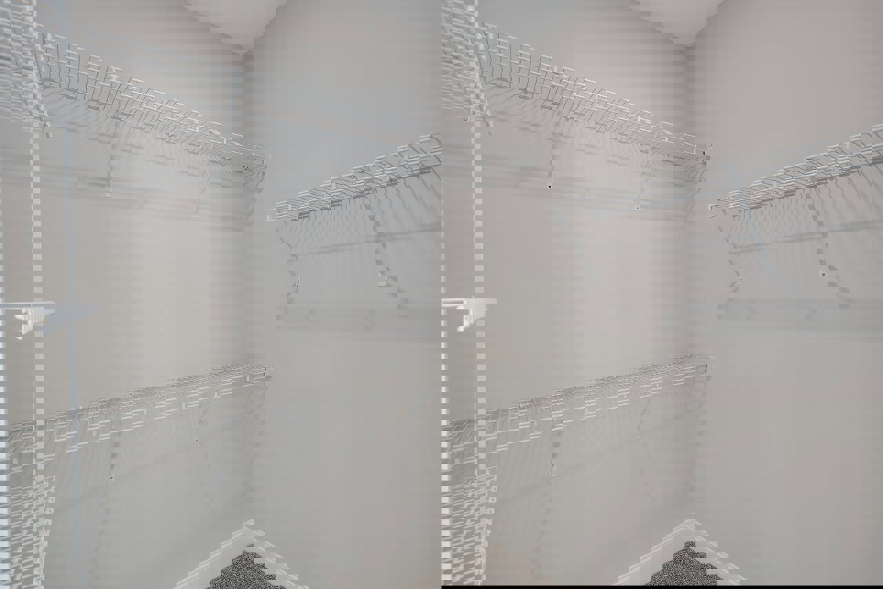 Bathroom with built-in white shelves, white rods, and carpeted floor; plaster walls and ceiling visible, radiator partially shown.