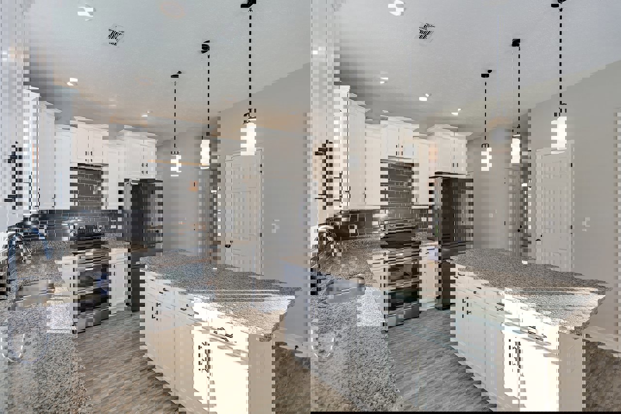 White kitchen cabinets, granite countertops, stainless steel oven with glass doors, stainless steel sink and faucet, white door with black handles, light-colored flooring