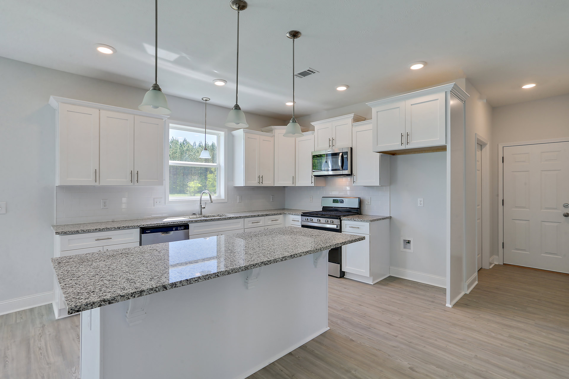 Granite countertops, stainless steel stove, built-in microwave with illuminated interior, undermount sink, dishwasher, white door with silver knob, vent and support pole, wood