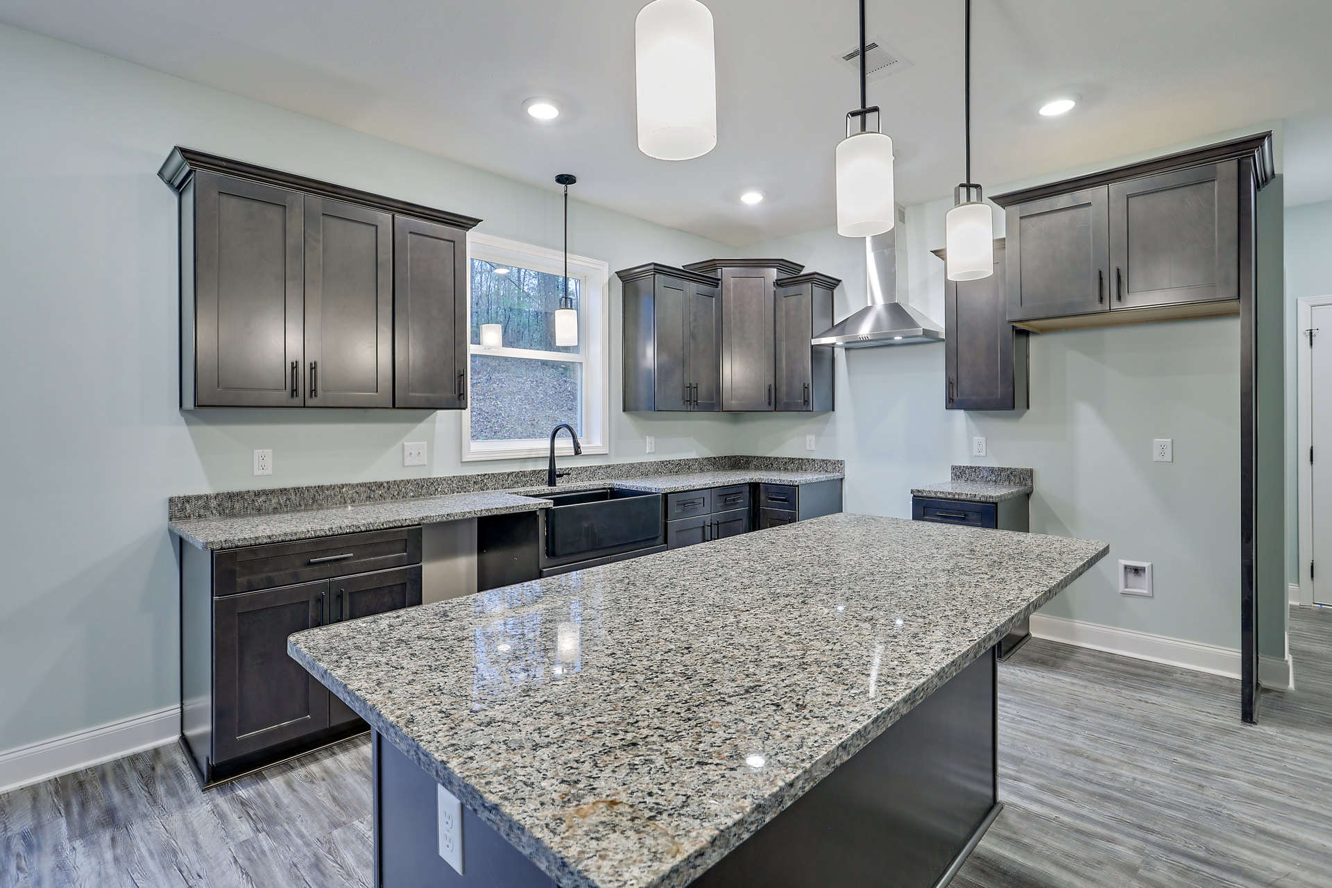 Granite countertops, dark cabinetry, black faucet, tile backsplash, stainless sink, and kitchen appliances