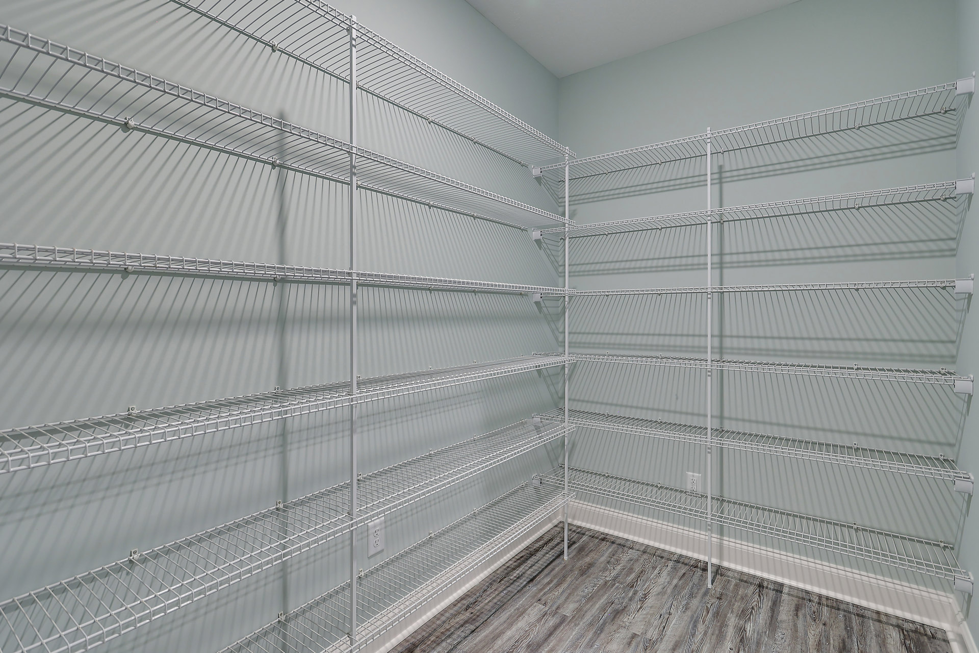 White built-in shelves along a wall, wood plank flooring, neutral painted walls, and recessed lighting in a modern residential room