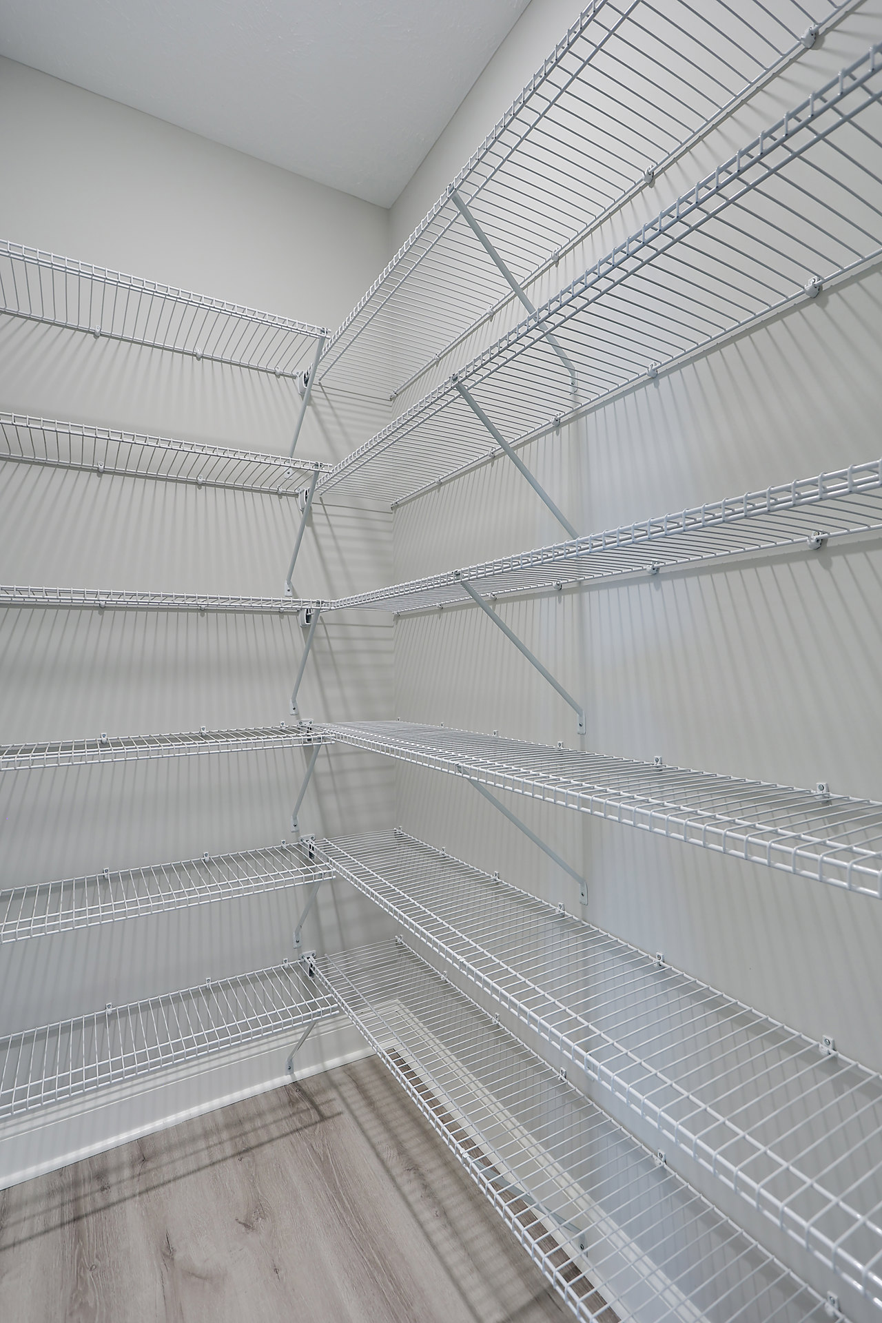 White built-in shelves with steel and aluminum accents against a brown wall in a symmetrical indoor room with composite materials and a ceiling visible.