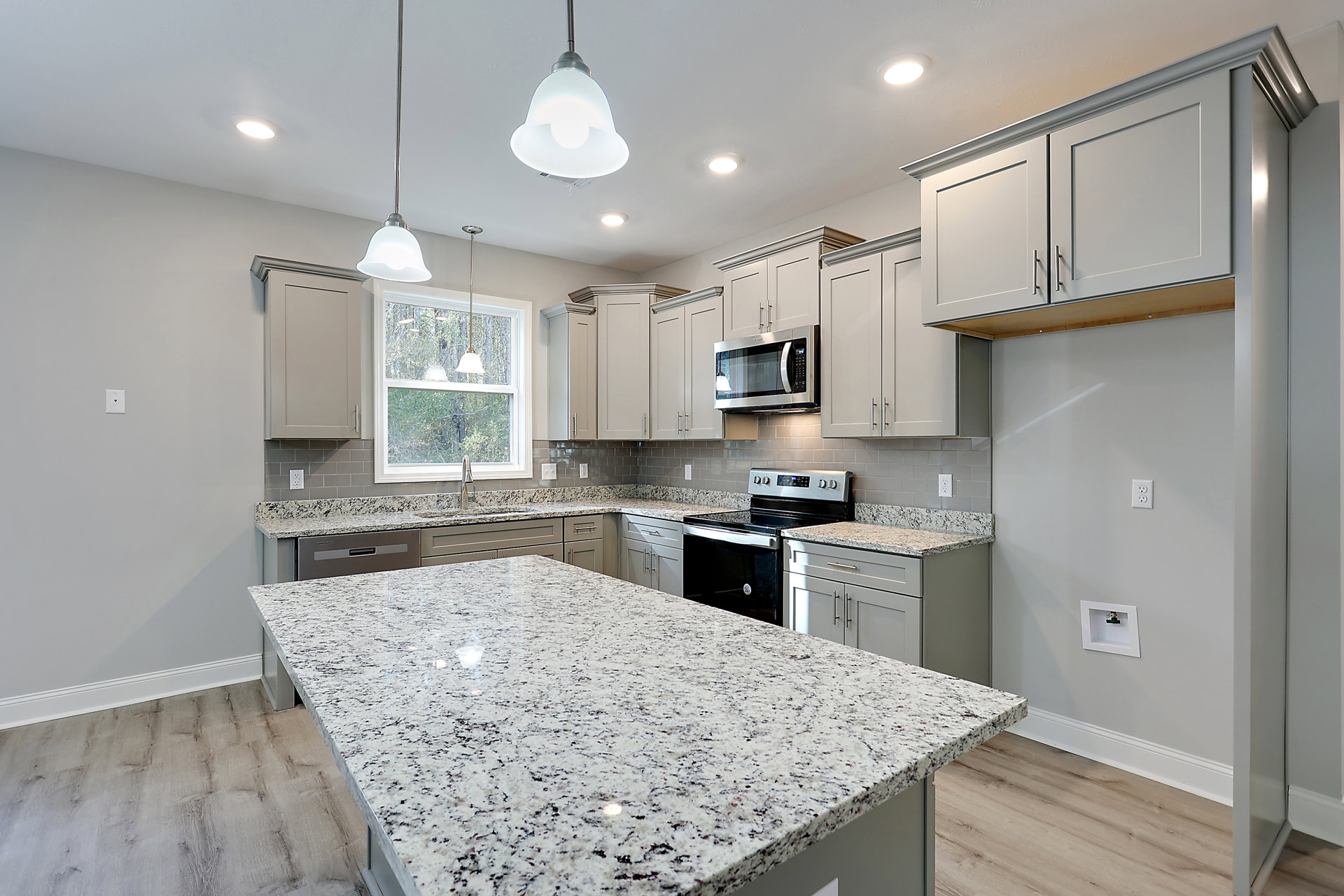 Granite countertops, wood cabinetry, stainless steel stove and oven, built-in microwave, tile backsplash, bell-shaped ceiling light fixture, undermount sink